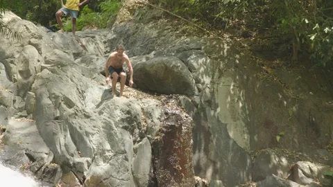 Man jumping off from a cliff into the plunge pool Stock Footage 87142142