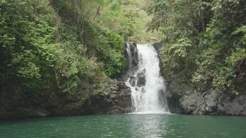 Man jumping off from a cliff into the plunge pool Stock Footage 87142689