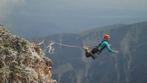 Man jumping off a cliff, rope jumping in the mountains. Stock Footage 97766248