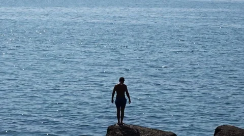 Man jumping off cliff into the sea Stock Footage 53315336