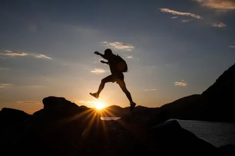 Man jumping on cliffs in sunset Stock Photos