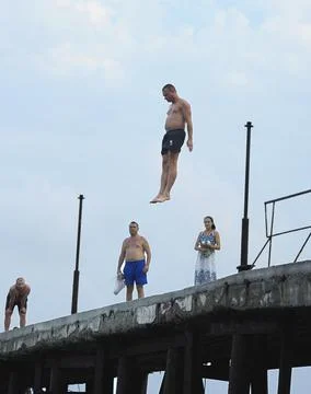 Man jumping down from the pier Stock Photos