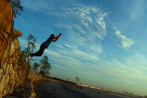 Man jumping from the embarkment of a river Stock Photos