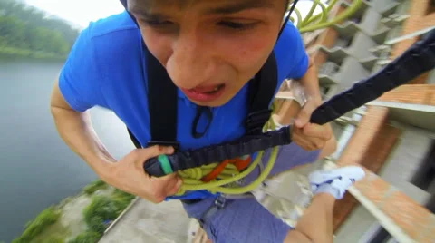 Man jumping facing forward clinging to a rope Stock Footage 48358832