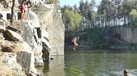Man jumping into granite quarry full of water. Slow motion Stock Footage 67897379