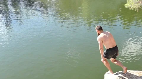 Man jumping into granite quarry full of water. Slow motion Stock Footage 67897395