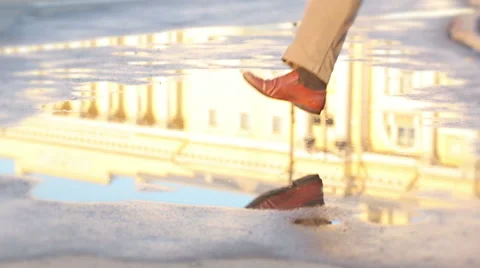 Man jumping happily in the puddle with beautiful reflection in sunny morning Stock Footage 67674611