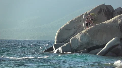 Man is jumping into the lake from rocks Stock Footage 66729779