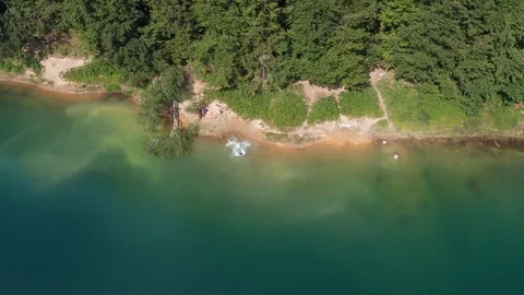 Man jumping in a mountain lake with a pine tree forest along the shore lines Stock Footage 120689953