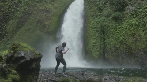 Man jumping next to waterfall Video stock 44350913