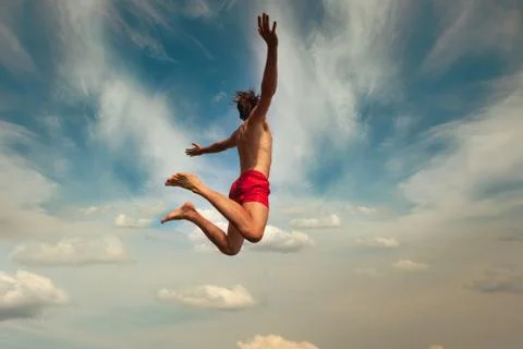 Man jumping over cloudly sky background. Outdoor adventure lifestyle. Summer fun Stock-Fotos
