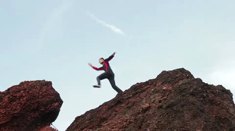 Man jumping over rocks in sunset Stock Footage 12203731