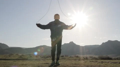Man jumping over a skipping rope on the background of sunlight Stock-Footage 61647745