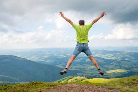 Man jumping on the peak of the mountain Stock Photos