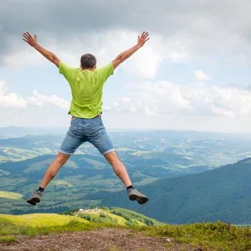 Man jumping on the peak of the mountain Stock Photos