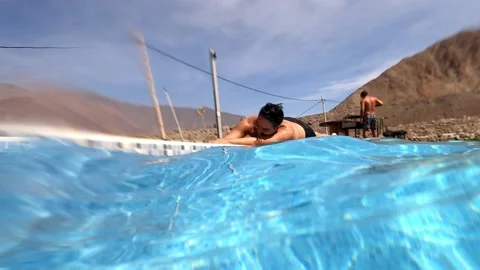 A man jumping into the pool rolling on the floor playing in a holiday cottage be Stock Footage 199558472