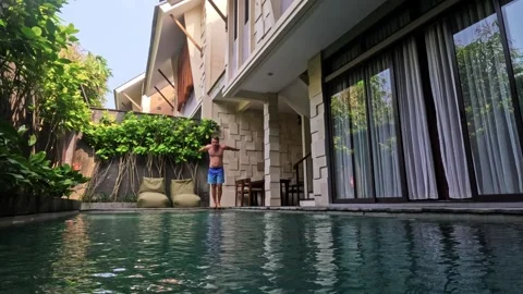Man jumping into private swimming pool at resort villa Stock Footage 340848062