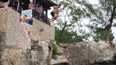 MAN JUMPING FROM THE ROCKS OF RICKS CAFE IN JAMAICA JUMP CAVE Stock Footage 83515658