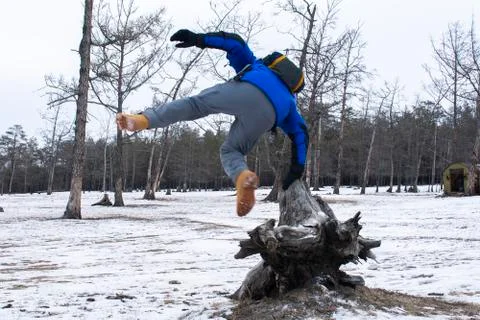 Man jumping from stump in the pine forest with snow on ground, winter in Russ Stock Photos
