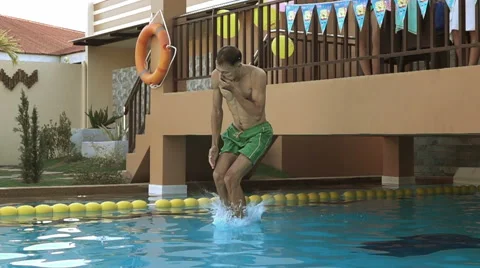 Man jumping in swimming pool. Slow motion entering the water. Stock Footage 62899637