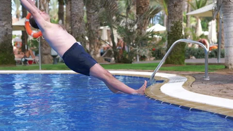Man jumping into swimming pool in slow motion 180fps Stock Footage 130779676
