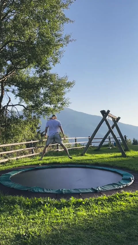 Man Jumping on Trampoline with Mountain View Stock Footage 329574359