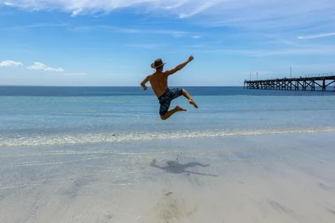A Man Jumping on a Tropical White Sand Beach of Australia 스톡 사진