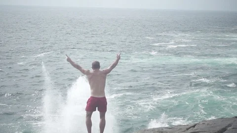 Man jumping when a wave breaks in slow motion Stock Footage 82315295