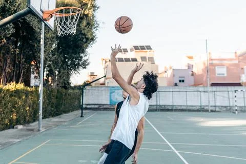 Man jumping while throwing a ball into a basket Stock Photos