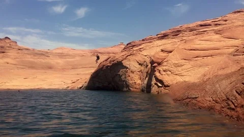 Man jumps off of cliff into lake HD Video stock 80236494