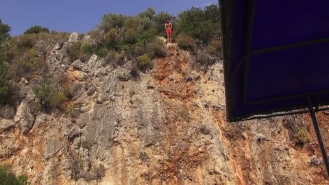 A man jumps from a cliff into the sea Video stock 70325381