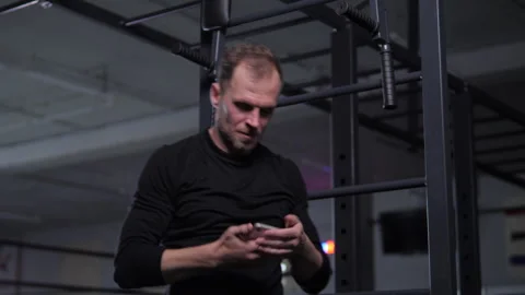 Man jumps off horizontal bar and looks at phone smiling Vidéo 312060061