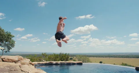 Man jumps into an infity pool Stock Footage 134304344