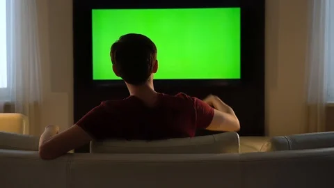 Man jumps over the couch and watches TV Stock Footage 121120741