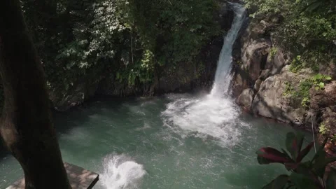 Man jumps off a platform into turquoise plunge pool Kroya Waterfall, Bali Stock Footage 313640449