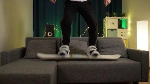 A man jumps on a snowboard on the couch Stock Footage 129387537