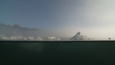 Man in a kayak moving on the water between pieces of ice on the Arctic Ocean Video stock 100605397