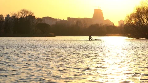 Man is kayaking alone in river at yellow beautiful sunset on city background Vidéo 129463653