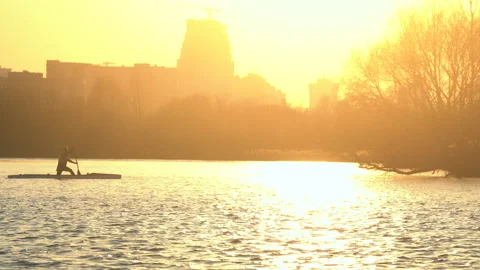 Man is kayaking alone in river at yellow beautiful sunset on city background Stock-Footage 131616194