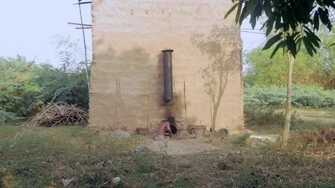 Man keeping the fire burning in a fireplace inside a barn for curing of tobacco Stock Footage 75169812
