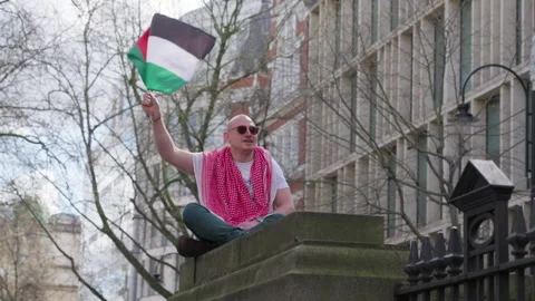 Man in Keffiyeh waves Palestinian Flag at Rally Against Gaza War in London Stock Footage 274563161