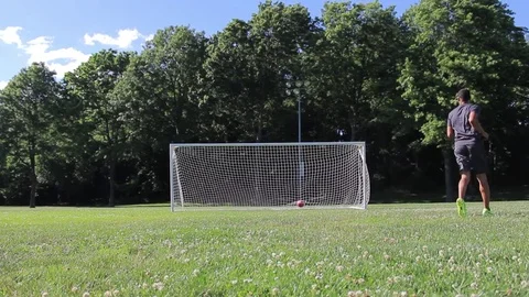 Man kicking soccer ball into empty soccer net Stock Footage 80071253