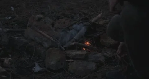 A man is kindling a campfire at dark time Stock Footage 165650855