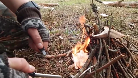 Man kindling a flame kindlin fire with flint Stock Footage 142029894