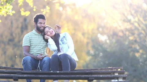 Man kissing woman on a cheek while they listening to music on earphones Stock Footage 59555873
