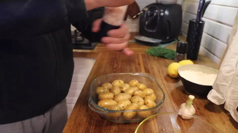 A man is in the kitchen baking young potatoes Stock Footage 274894213