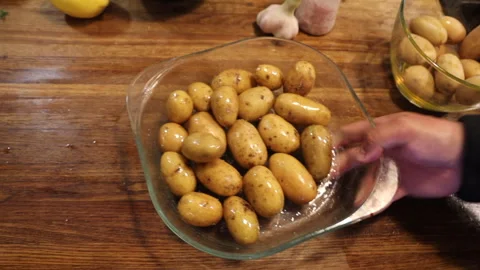 A man is in the kitchen baking young potatoes 스톡 동영상 274894243