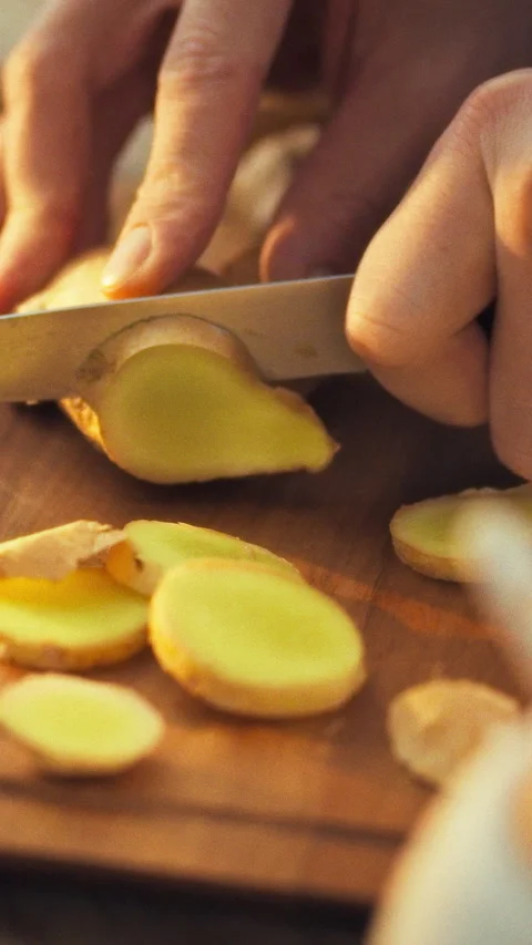 Man in a kitchen chops fresh ginger rhizome on a cutting board the pungent a Stock Footage 342717546