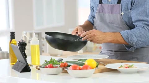 Man in kitchen cooking dish and using digital tablet Stock Footage 56062626