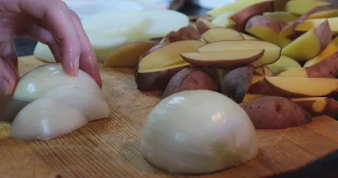 A man in the kitchen cuts onions with a knife on a wooden chopping board. Stock Footage 168558288